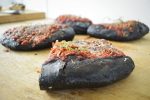 Sliced pizza with black colored crust from charcoal infused dough